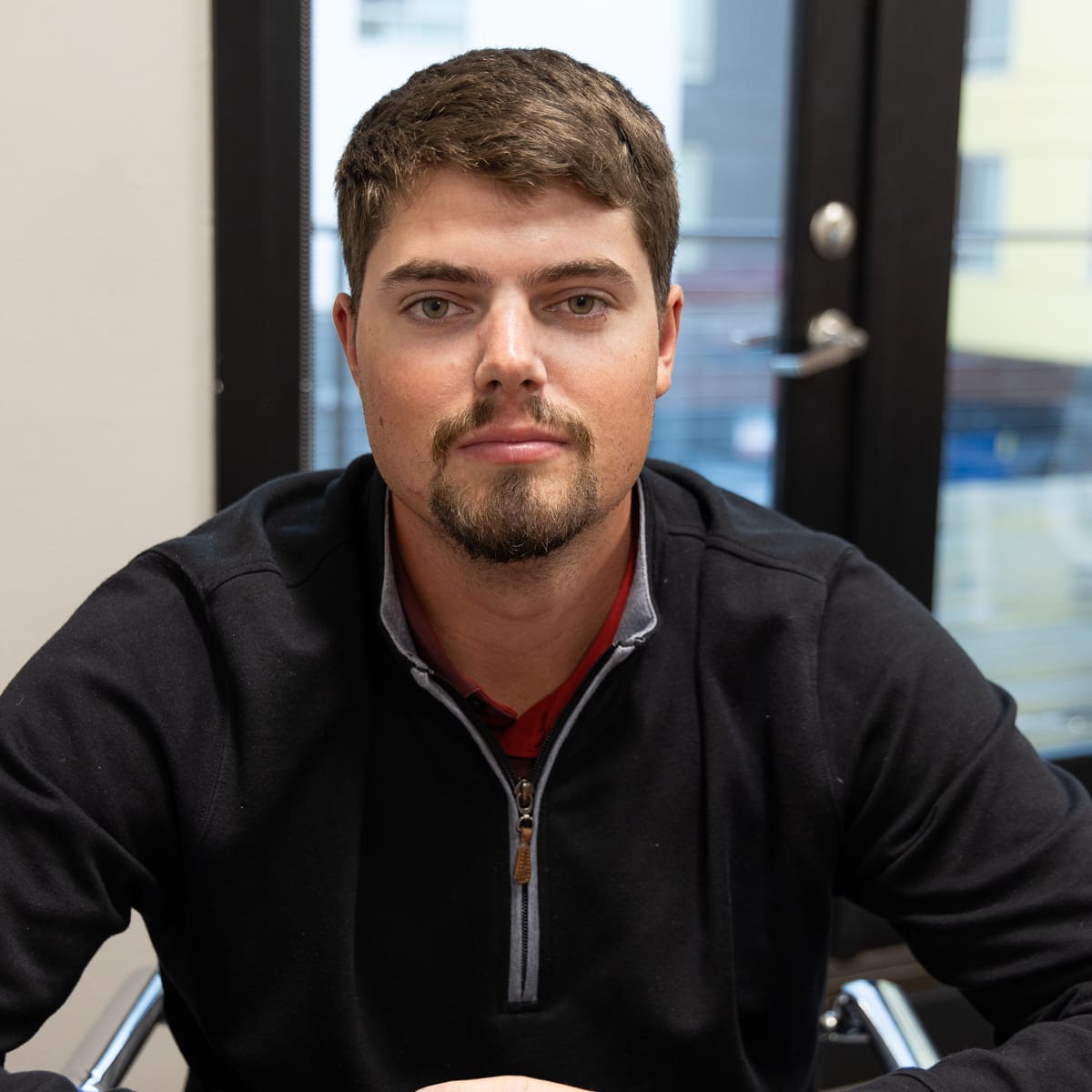 Project Manager Jacob Zeman A man with a goatee and short brown hair sits in an office looking at the camera