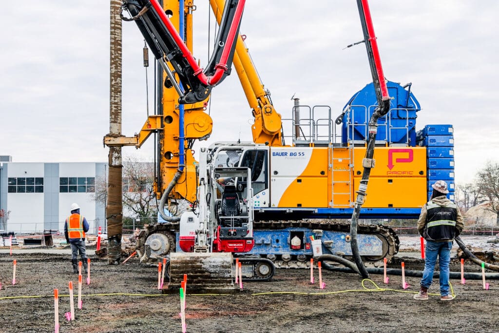 A yellow and blue Bauer BG 55 vertical drill rig performs CFA pile installation at a data center construction site in Hillsboro, Oregon